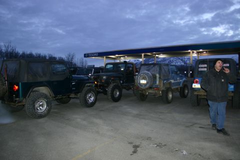 2003 Jeep TJ - Multiple Jeeps are parked at a gas station under a cloudy sky.