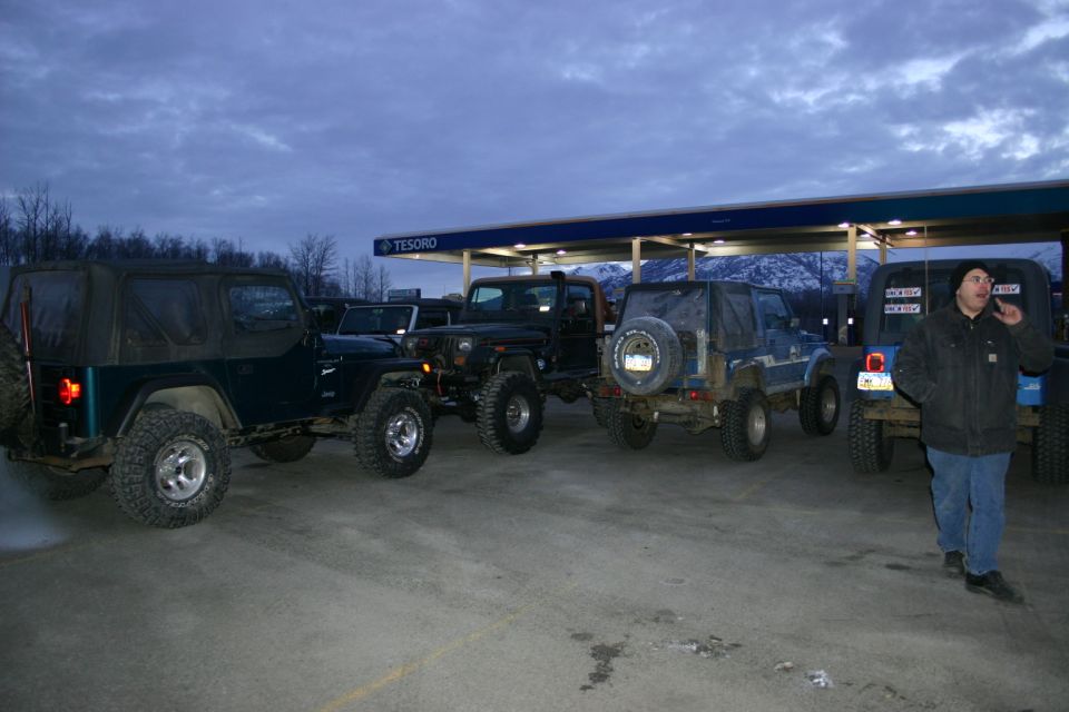 Several Jeeps parked under a Tesoro gas station canopy at dusk