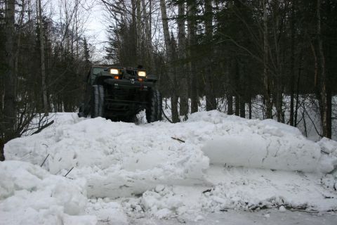 2003 Jeep TJ - An all-terrain vehicle navigates a snowy path in a wooded area.