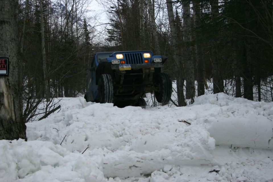 Blue Jeep Wrangler driving through deep snow. License plate EBG-770