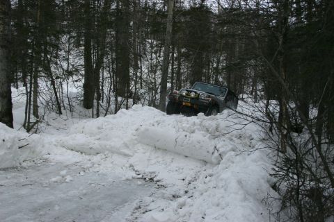 2003 Jeep TJ - A Jeep TJ navigates a challenging snowy path in a wooded area.