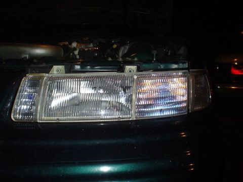 1993 Ford Taurus - Front view of a 1993 Ford Taurus headlight assembly, hood is open showing engine components.