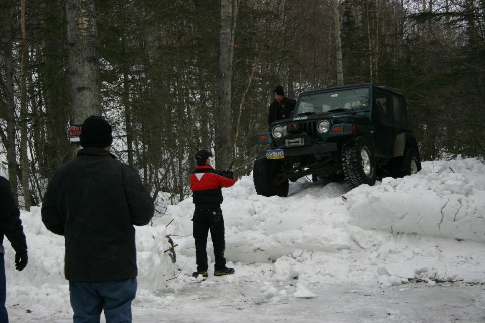 Jeep TJ stuck in snowbank, people around it
