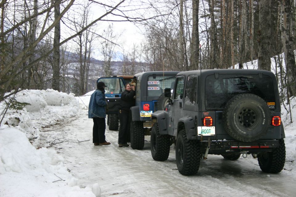 Three black Jeep Wranglers parked on a snowy road, rear view. The closest Jeep has a spare tire on the back and a license plate reading 'ROOT'