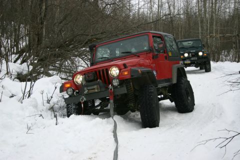 2003 Jeep TJ - Two Jeeps navigate a snow-covered path through a wooded area.