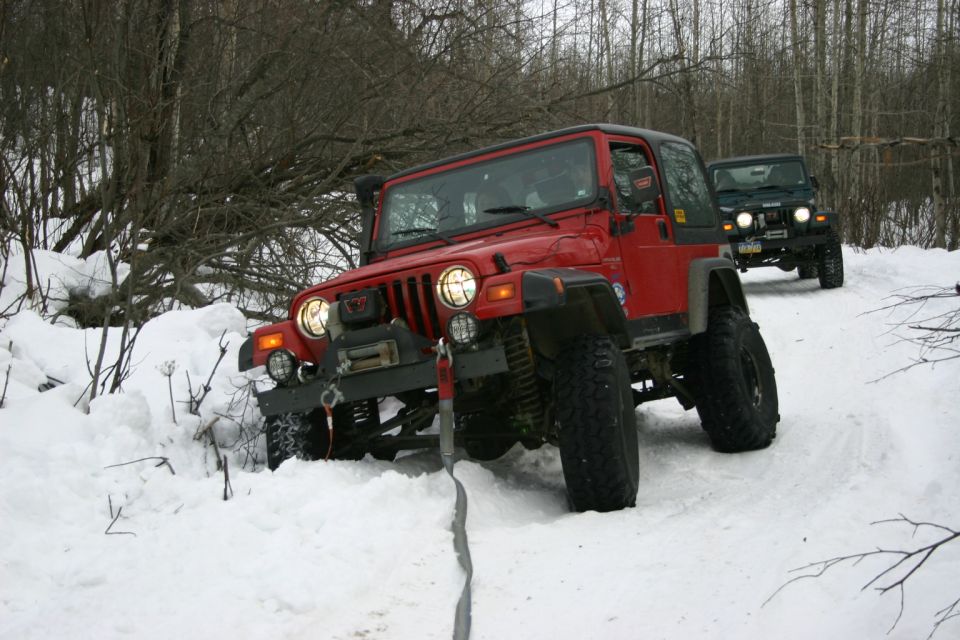 Red 2003 Jeep TJ and another Jeep driving on a snowy trail