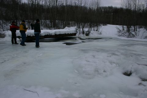 2003 Jeep TJ - Three individuals observe a frozen waterway surrounded by snow-covered trees and brush.