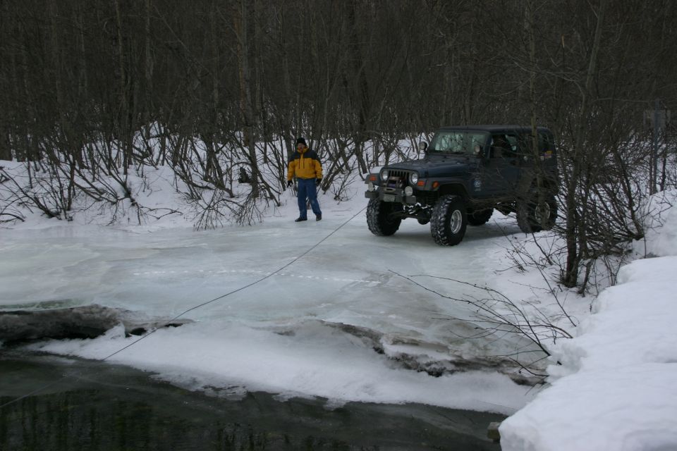 Dark blue 2003 Jeep TJ on icy road with a person standing nearby