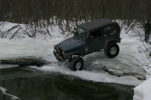 2003 Jeep TJ - A dark blue Jeep TJ navigates a frozen body of water with a tow rope attached.