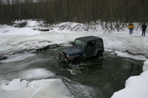 2003 Jeep TJ - A dark blue 2003 Jeep TJ navigates a partially frozen river during winter.