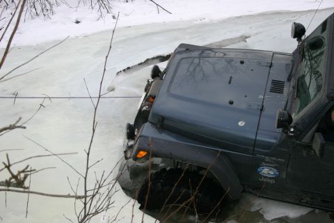 2003 Jeep TJ - A Jeep Wrangler navigates through a partially frozen body of water during winter conditions.