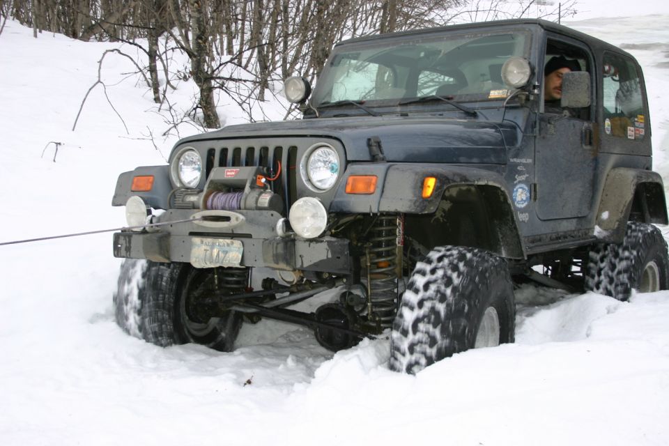Dark blue Jeep TJ with a winch is stuck in deep snow, front view