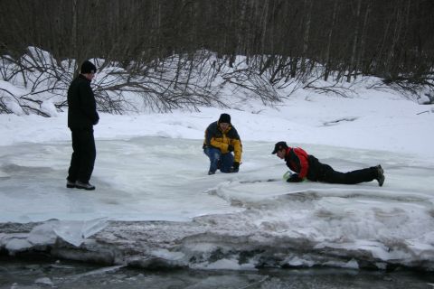 2003 Jeep TJ - Three individuals are on a frozen surface surrounded by snow and trees.
