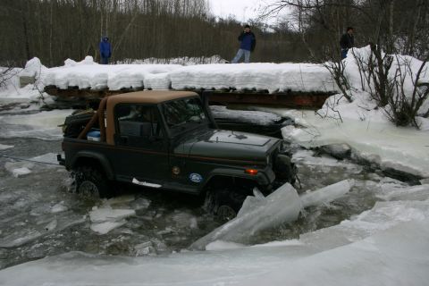 2003 Jeep TJ - A green 2003 Jeep TJ is shown driving through a partially frozen body of water with ice chunks around it.