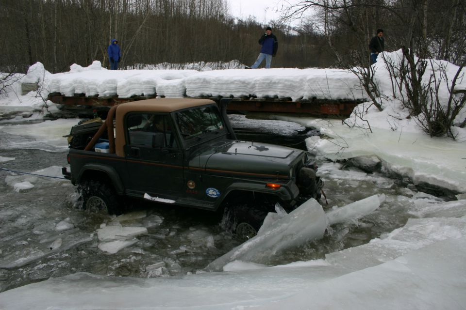 Green 2003 Jeep TJ navigating icy water