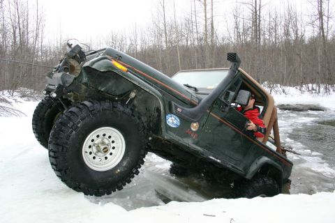 2003 Jeep TJ - A modified Jeep Wrangler TJ navigates a challenging icy terrain, with one wheel deep in the water.