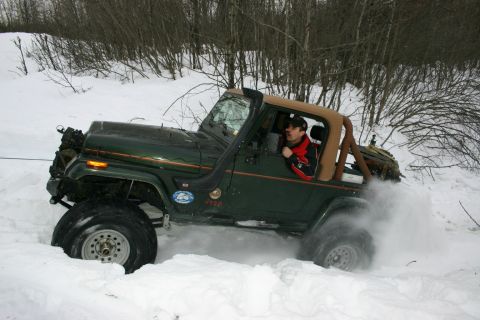 2003 Jeep TJ - Jeep Wrangler struggling in deep snow, driver visible inside.