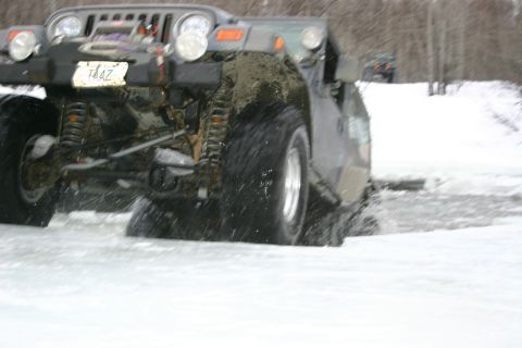 2003 Jeep TJ - A Jeep TJ navigates a snowy, watery terrain, with a second vehicle visible in the distance.