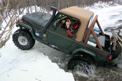 2003 Jeep TJ - A 2003 Jeep TJ drives through icy water, its snorkel and off-road tires evident.