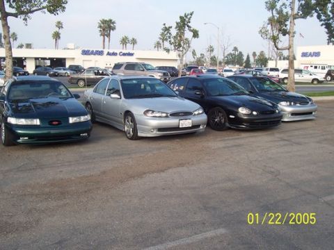 2002 Ford Taurus - Multiple sedans are parked in a lot with a Sears Auto Center in the background.