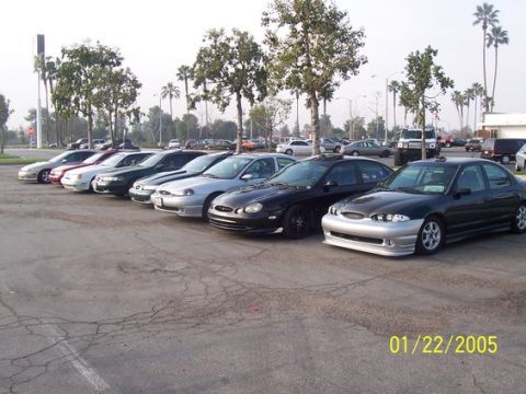 2002 Ford Taurus - A row of cars are parked in an outdoor lot, with a date and website watermark in the lower right corner.