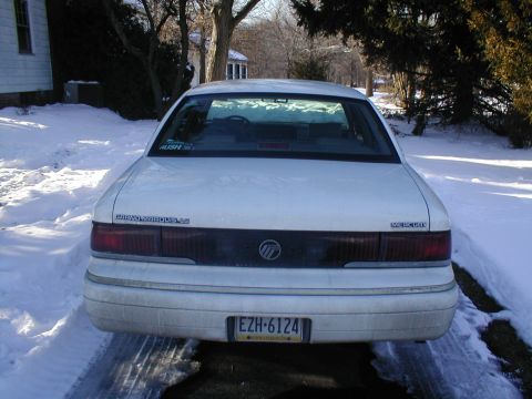 1979 Ford Bronco - A white Mercury Grand Marquis LS is parked in a snowy driveway, showing its rear end and license plate.