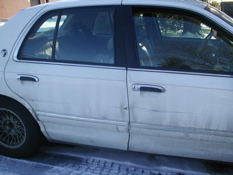 1979 Ford Bronco - A white sedan with a dent on the rear door is parked on a snowy surface.