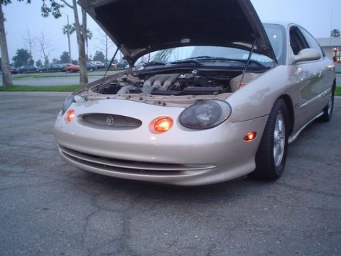 2002 Ford Taurus - A tan Mercury Sable is parked with its hood up, revealing the engine compartment.