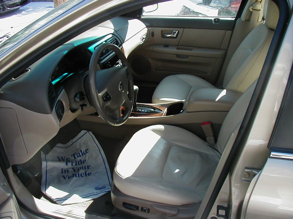 Car interior with leather seats and floor mat that says "We Take Pride in Your Vehicle."