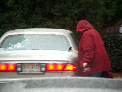 1998 Ford Taurus - A person scrapes ice from the rear window of a 1998 Ford Taurus sedan.