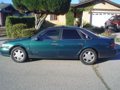 1993 Ford Taurus - Side view of a green 1993 Ford Taurus sedan parked in a driveway.