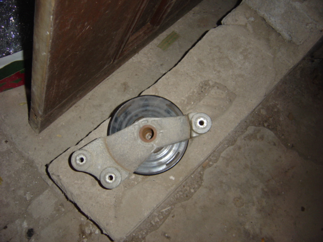 Polished underdrive crank pulley with a metal bracket on a concrete floor