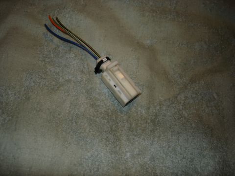 1999 Ford Contour - A close-up view of a white plastic electrical connector with multiple colored wires extending from it.