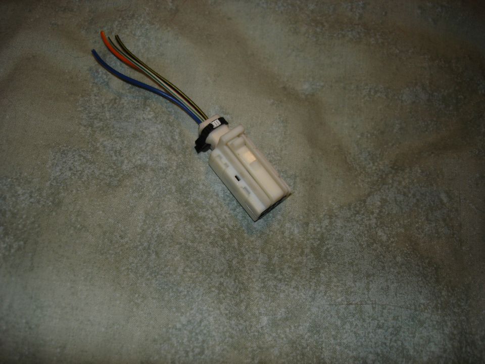 Wiring harness connector with blue, orange, and green wires attached