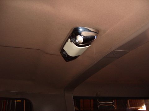 1993 Ford Bronco - Close-up of a chrome-bezel dome light mounted in the tan headliner of a truck cab, shot looking upward with the rear side window and roof s…