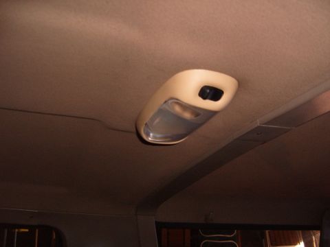 1993 Ford Bronco - Factory-style tan plastic dome light with a clear lens and black rocker switch installed in the tan headliner of a truck cab, shot looking…