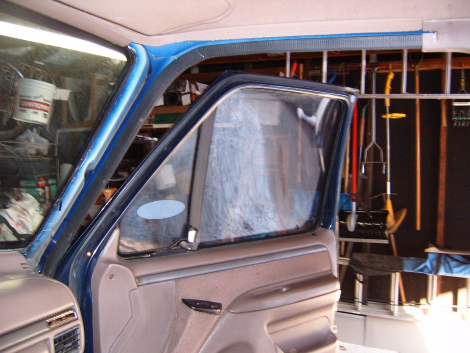 Open passenger door on blue truck with tan door panel, shot inside a tool-lined garage