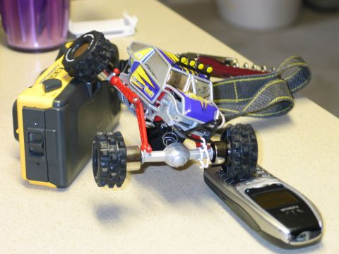 1992 Ford Bronco - A remote-controlled rock crawler toy is positioned on top of a cell phone and a yellow electronic device.
