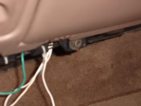 1993 Ford Bronco - Close-up inside a vehicle showing white and green speaker wires routed under a tan plastic door sill trim panel onto brown carpet. The kick…