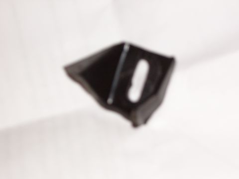 1993 Ford Bronco - Out-of-focus close-up of a small black molded plastic bracket or trim piece with an oval slot and an internal rib, photographed loose again…