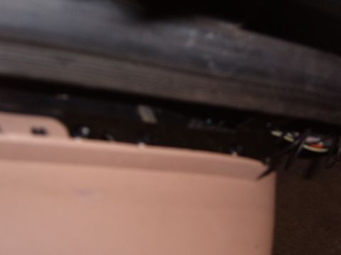 1993 Ford Bronco - Blurry close-up inside a vehicle showing a tan interior panel pulled away from the door sill, exposing a black wiring harness with white, r…