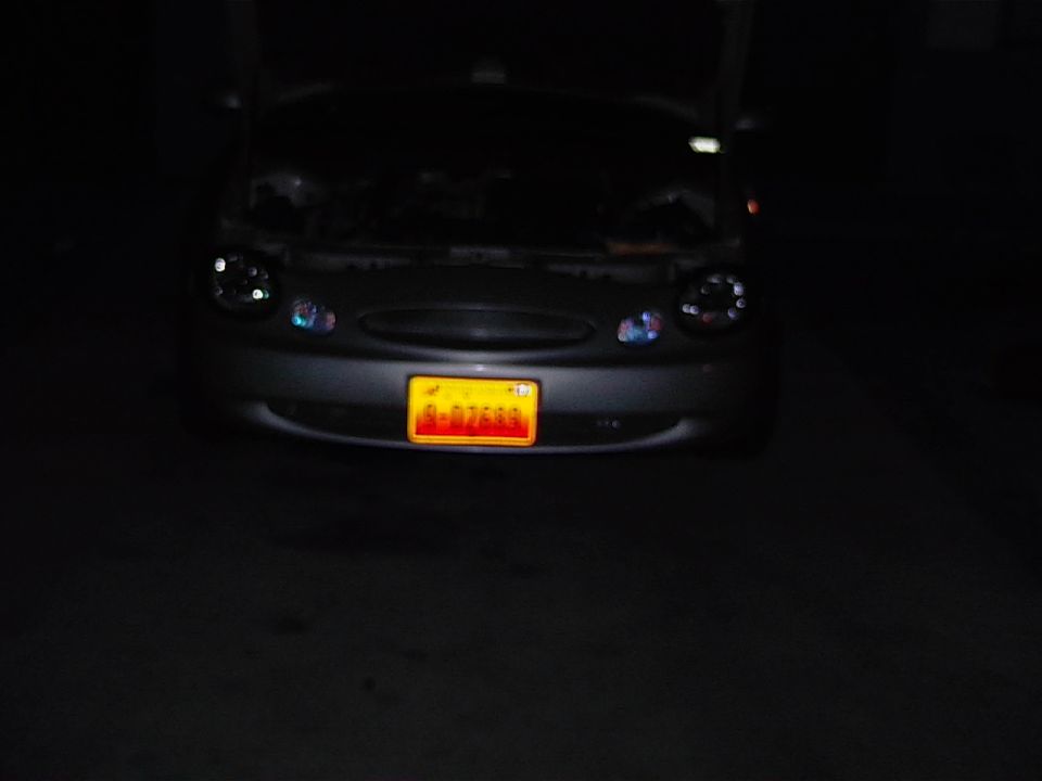 Front view of a 1999 Ford Taurus with its hood open and a yellow license plate