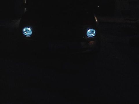 1999 Ford Taurus - The front of a dark vehicle is visible at night, with its headlights illuminated.