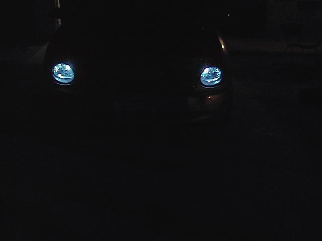 Dark car front with illuminated headlights