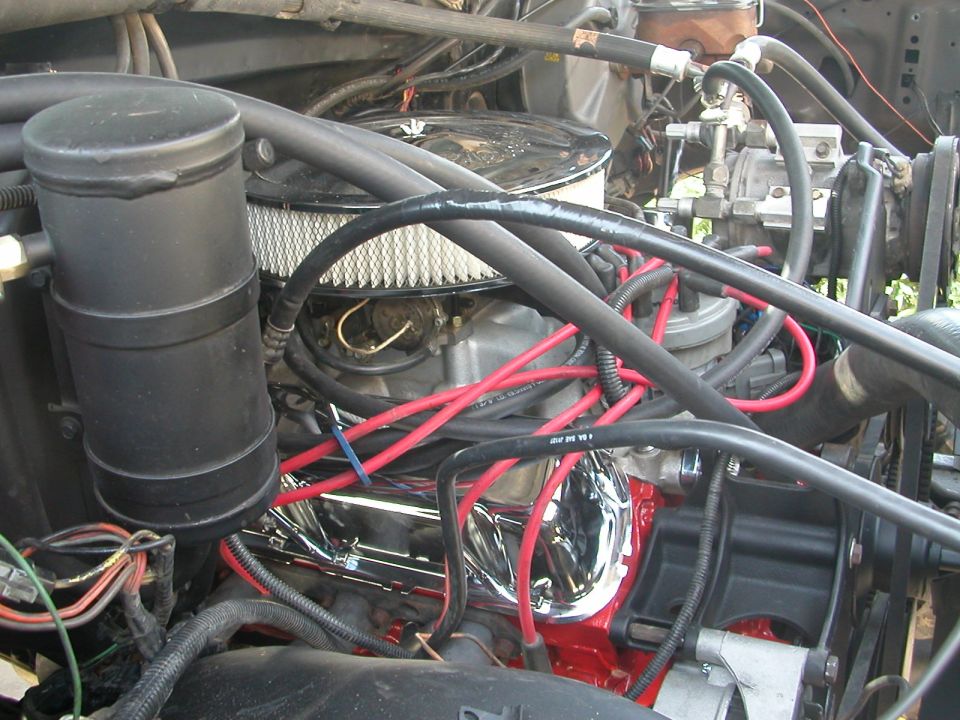 Carbureted V8 engine bay with air cleaner, red plug wires and black canister