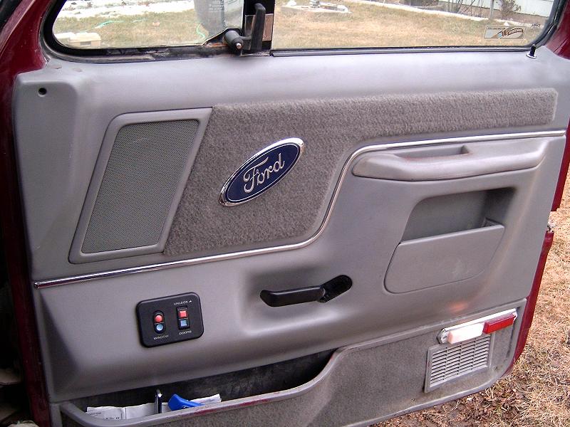 Gray Ford truck door panel with blue Ford oval, carpet insert and power-window switches