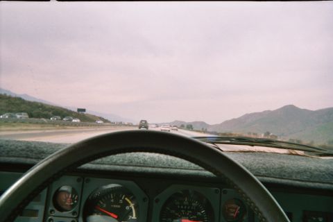 1985 Ford Mustang - Driving on a highway with traffic visible from the car's interior.