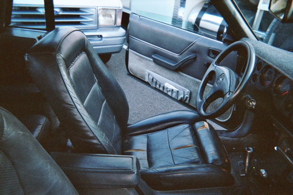 Fox-body Mustang black leather driver seat, grey door panel and four-spoke steering wheel