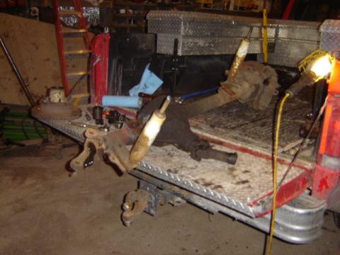 1992 Ford Bronco - Various automotive parts, including an axle and shocks, are laid out on the bed of a pickup truck for repair.