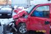 1990 Ford Taurus - Damaged red pickup truck in a parking lot, with another vehicle behind it.